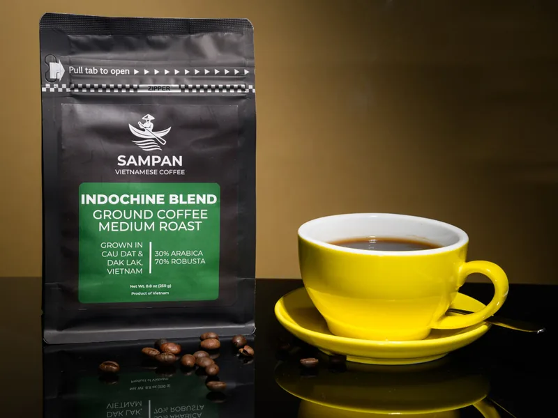Sampan Indochine Blend Vietnamese coffee bag beside a yellow cup of freshly brewed coffee